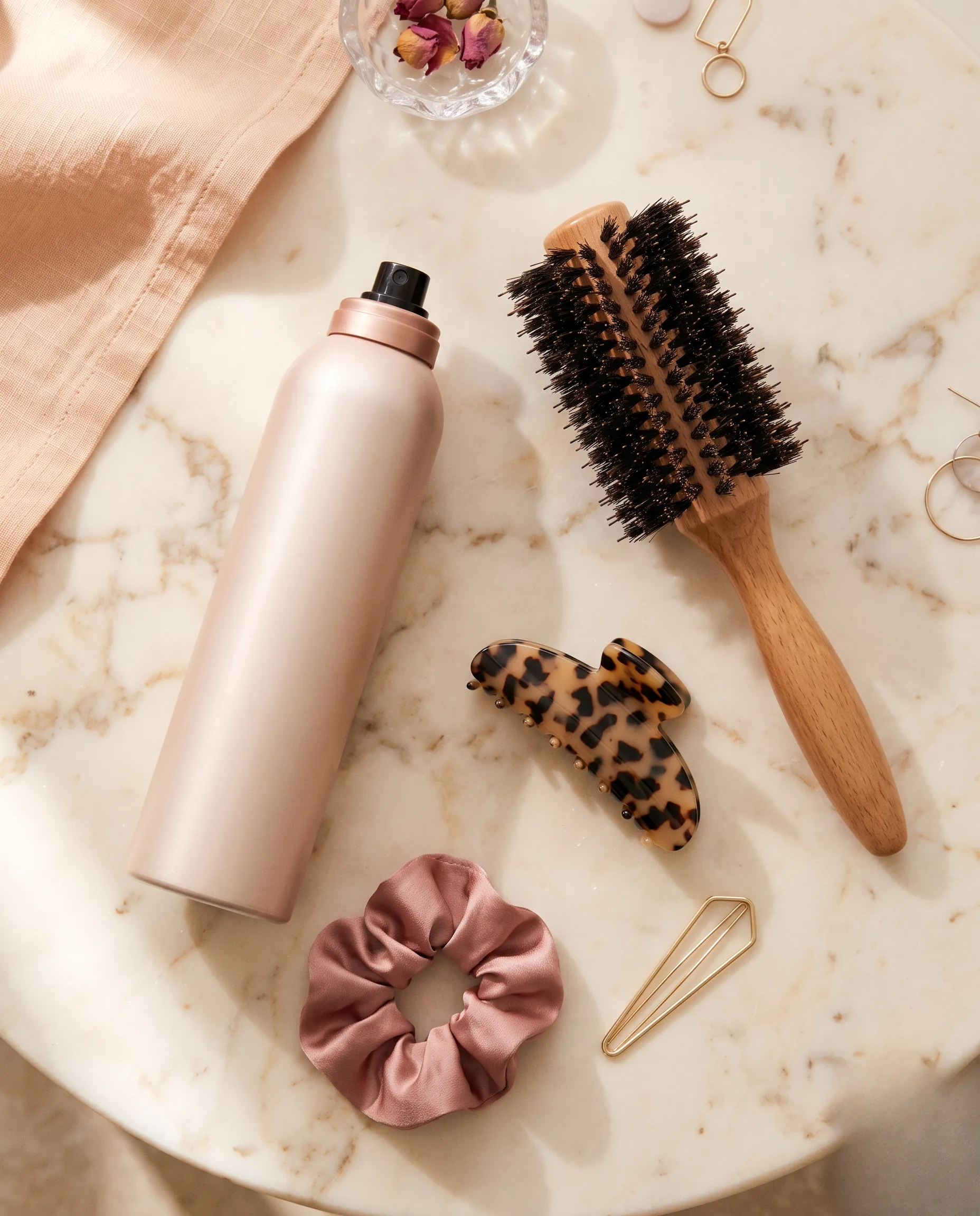 Flatlay esthétique de produits de coiffage et d'accessoires pour cheveux courts sur fond marbré.